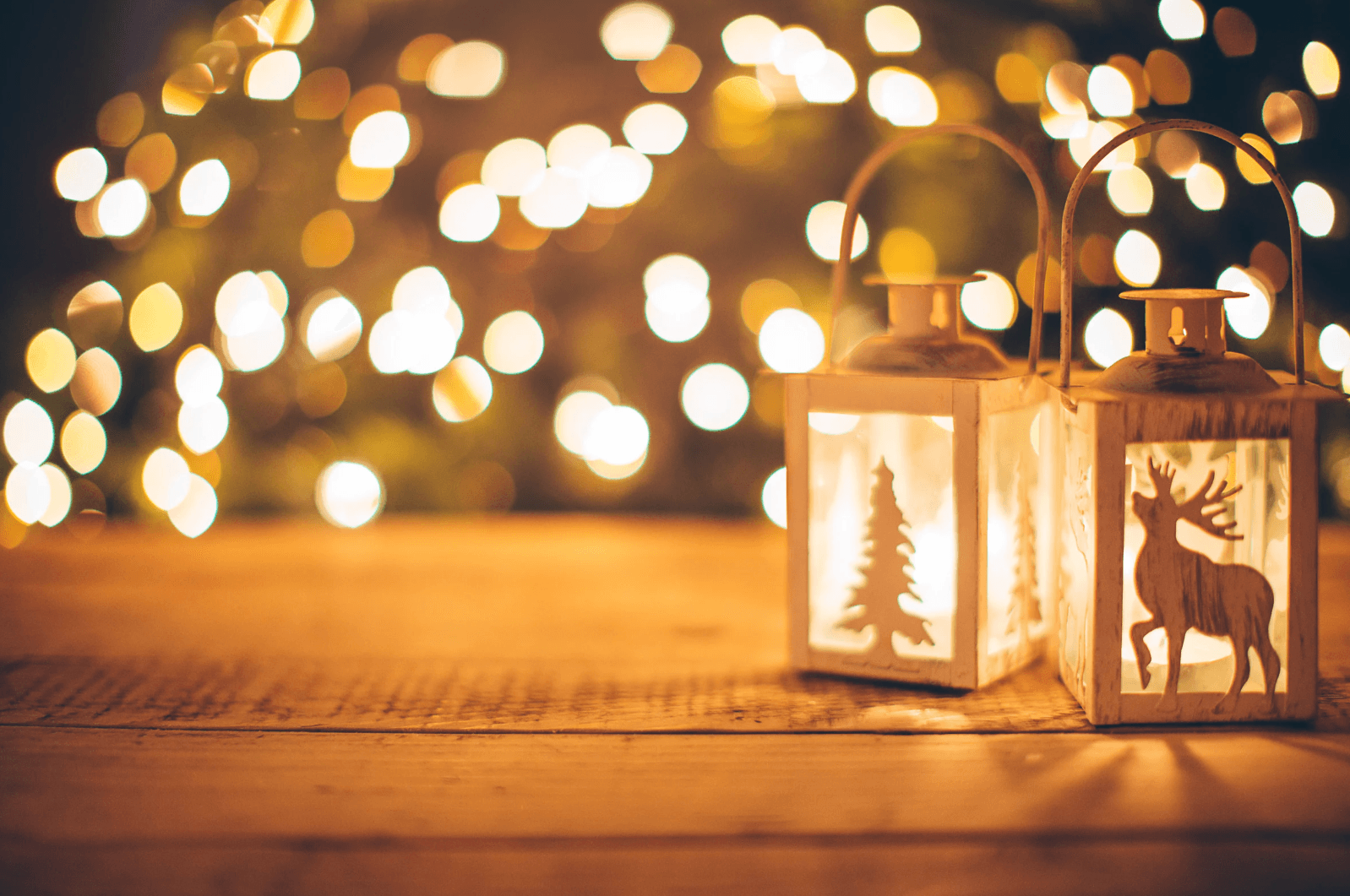 Blurred festive lighting with two candle-holders - one with a Christmas tree and one with a raindeer